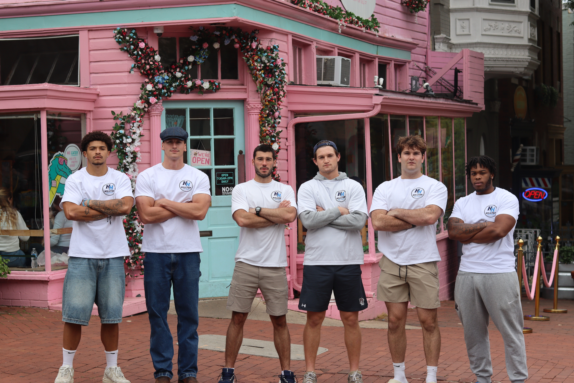 Hilltop Helpers crew in branded shirts in front of the Georgetown pink Martin's Tavern building