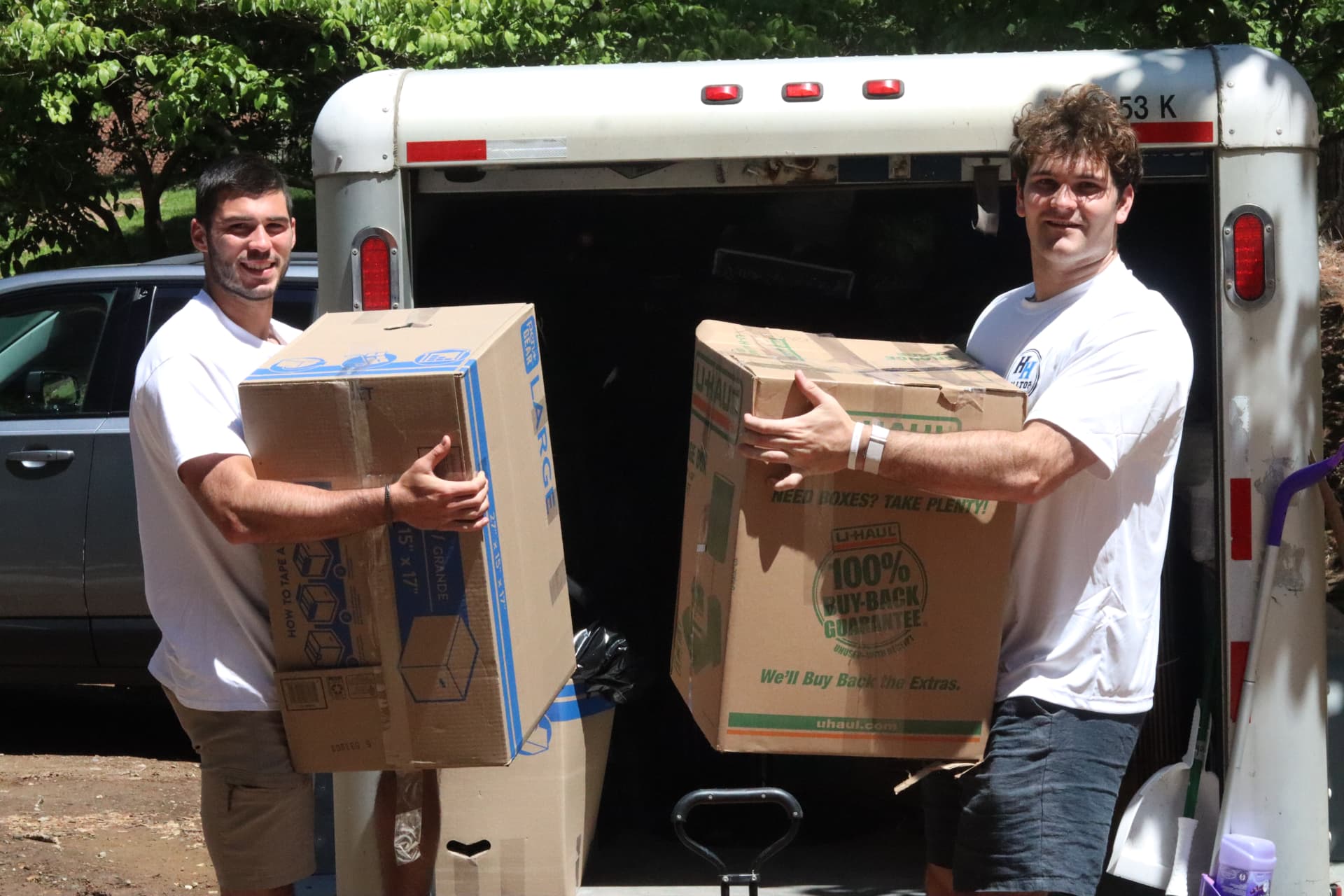 Hilltop Helpers crew carrying moving boxes in front of a moving truck