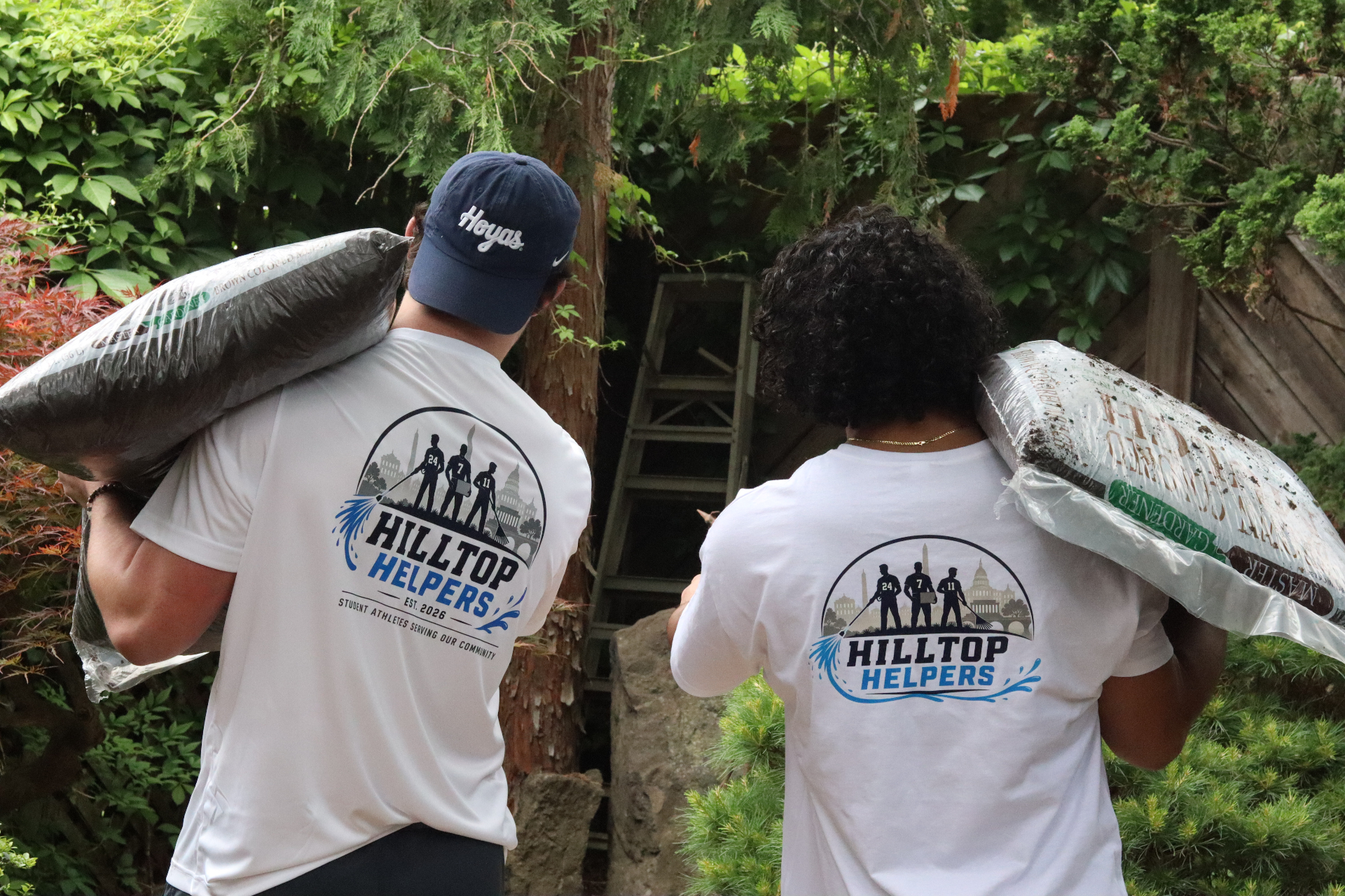 Hilltop Helpers crew carrying mulch bags through a garden